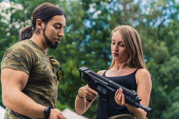 Male caucasian muscular shooting instructor in moro t-shirt showing the types of rifles to his...
