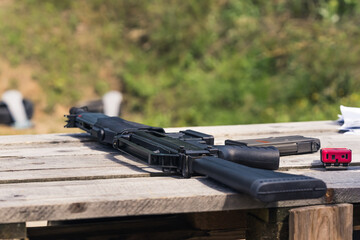 Unused black shotgun placed on a wooden table. Outdoor shot. Day at a shooting range concept....