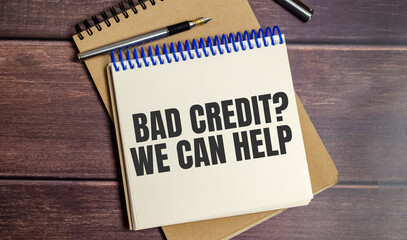 bad credit we can help, text on wooden background and pen