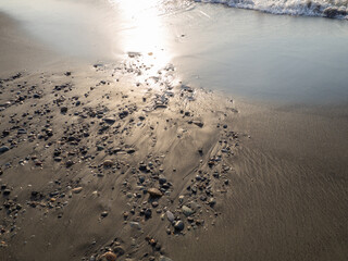 Stones on the sandy beach. Quiet place. The silence of the waves Edge of the coast. Background of sand and stone. Black sand on the beach.