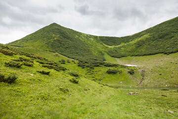 Glacial mountain lake under a green peak