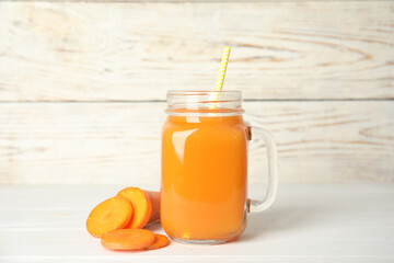 Freshly made carrot juice in mason jar on white wooden table