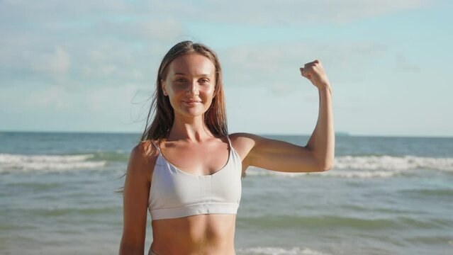 portrait woman after workout looks at camera demonstrate biceps arm.