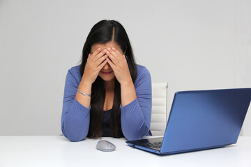 Dark-haired latin adult woman works in her office with laptop with a lot of stress having a...