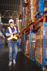 Happy Asian senior supervisor working - inspecting an items in the warehouse.