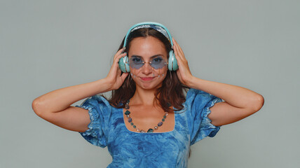 Happy young woman in blue princess dress listening music and dancing disco fooling around having fun expressive gesticulating hands, relaxing on party. Stylish girl alone on gray studio background