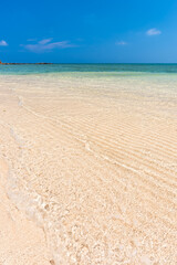 Incredible crystal clear turquoise water, gentle waves lapping over white sands on an idyllic beach.