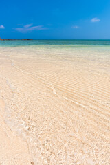 Incredible crystal clear turquoise water, gentle waves lapping over white sands on an idyllic beach.