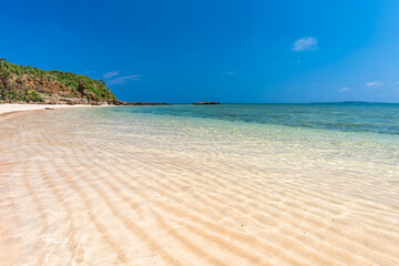 Amazing crystal clear water sea over wavy sands, cliff mountain, blue sky on a paradise beach. Japan.