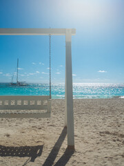 Dominican Republic, a beautiful beach with white sand and azure ocean. White beautiful swing for relaxing on the shore