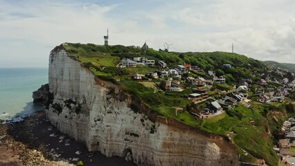 Modern cottages on a gentle hill which side is a sheer cliff, washed by the waters of the English Channel. Aerial view, Etretat, France.