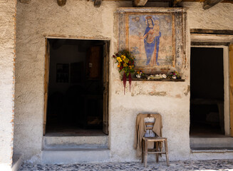 Side entrance at a historic Swiss farmhouse protected by a picture of Maria and Jesus