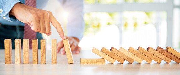 Close-up hand prevent wooden block not falling domino concepts of financial risk management and...