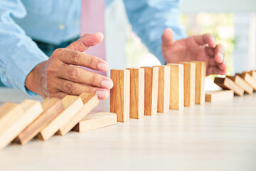 Close-up hand prevent wooden block not falling domino concepts of financial risk management and...