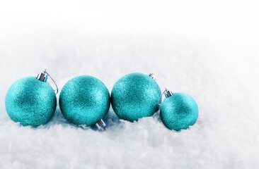 Beautiful blue Christmas balls on snow against blurred background. Space for text