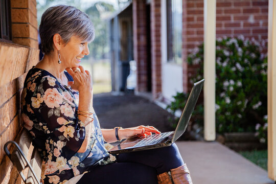 Smiling middle aged woman using her laptop to talk with grandkids