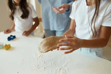 Two little sisters cook food in the kitchen, play with flour, draw figures with their fingers on the table