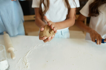 two little girls and their beautiful mother in aprons play and laugh, roll out cookie dough. bakery products