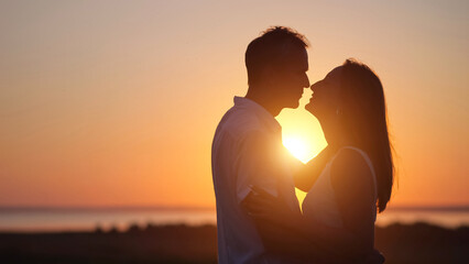 Husband expresses true love to gorgeous wife at back sunset. Couple silhouettes look at each other...
