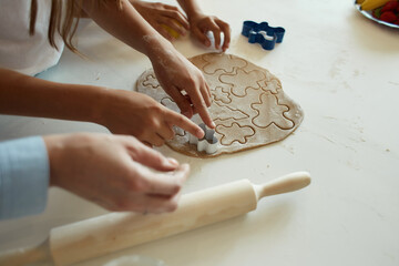 two little girls and their beautiful mother in aprons play and laugh, roll out cookie dough. cut beautiful shapes