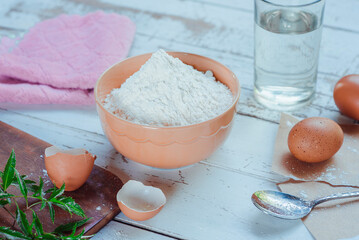 Wheat flour in a bowl and an egg placed near it.