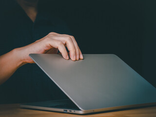 Man open or close laptop cover lid on wooden table by hand. Starting working or job done using...