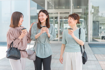 コーヒーを持ちながら話すアジア人女性（同僚、ママ友、女友達）

