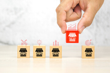 Close-up hand choose wooden block stack with franchise business store icon for franchising to...