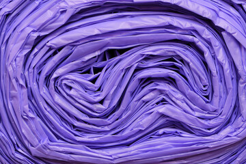 Extreme close-up end of tightly packed roll of non-recyclable purple rubbish garbage trash bags