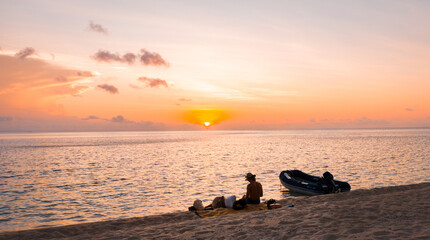 Naklejka na ściany i meble silhouette of a couple watching the sunset on a beach