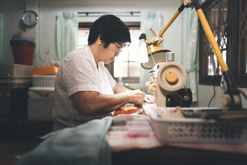 Retriement tailor southeast asian elderly crafting a cloth by sewing machine working at home