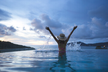 Rear view of woman hand raised happy relax at outdoor pool resort sea panorama sky view in southeast asia tropical