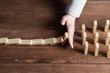 Businesswoman protecting dominoes from falling