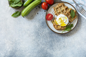 Spinach and zucchini vegan waffles with a poached egg on a stone tabletop. The concept of dietary and healthy breakfast. View from above. Copy space.