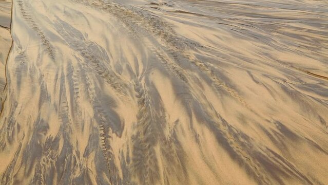 Sea water flowing at low tide on a beach creating patterns of light and dark in the vicinity of the village of Liencres, Cantabria Spain