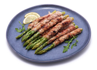 Healthy food - Asparagus wrapped with bacon and spices on a plate isolated on white background