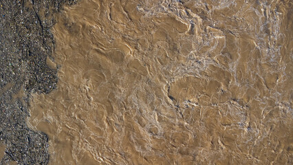 Aerial view of water released from the drainage channel of the concrete dam is a way of overflowing water in the rainy season. Top view of turbid brown forest water flows from a dam in Thailand.
