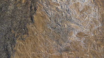 Aerial view of water released from the drainage channel of the concrete dam is a way of overflowing water in the rainy season. Top view of turbid brown forest water flows from a dam in Thailand.