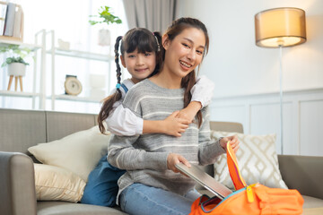 Asian mother help her daughter wearing school bag to prepare go to school.