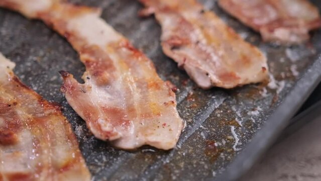 cooking Pieces of flavorful sliced organic bacon fried in grill pan