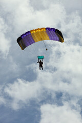 Skydiver silhouette under the parachute canopy against the sky with clouds.