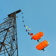 Base jumper jumps with a parachute from an abandoned metal antenna on a background of blue sky. The sequence of movement of the jumper and the deployment of the parachute canopy, panorama.
