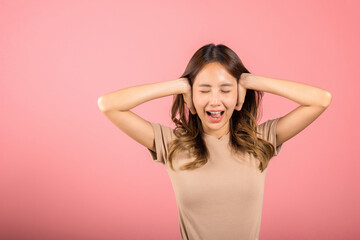 Fototapeta premium Asian portrait beautiful young woman have close ears with hand palms and close eyes, studio shot isolated on pink background, Thai female covering ears for loud noise with copy space, bad pressure