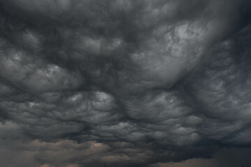 Czarne, ciężkie, pofałdowane burzowe chmury.  Budzą one grozę zapowiadając nadejście gwałtownych opadów i wiatru stanowiącego zagrożenie dla życia. - 526438850