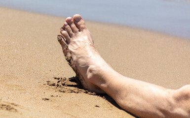 Feet of a man on the seashore.