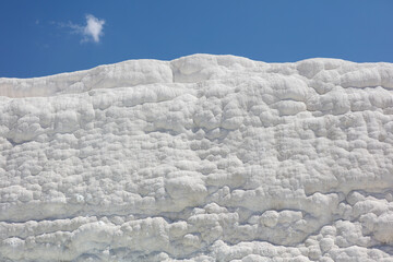 A mountain of white volcanic limestone rock against a blue sky.