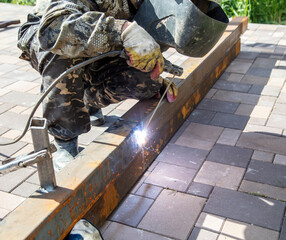 A worker works with metal welding at a construction site.