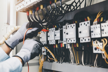 Electrical engineer using digital multi-meter measuring equipment to checking electric current...