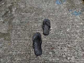 A pair of patterned black flip-flops on the cement floor.
