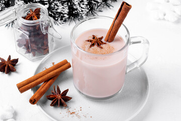 Masala tea in glass mug with cinnamon, anise and milk. Indian hot winter drink on white table